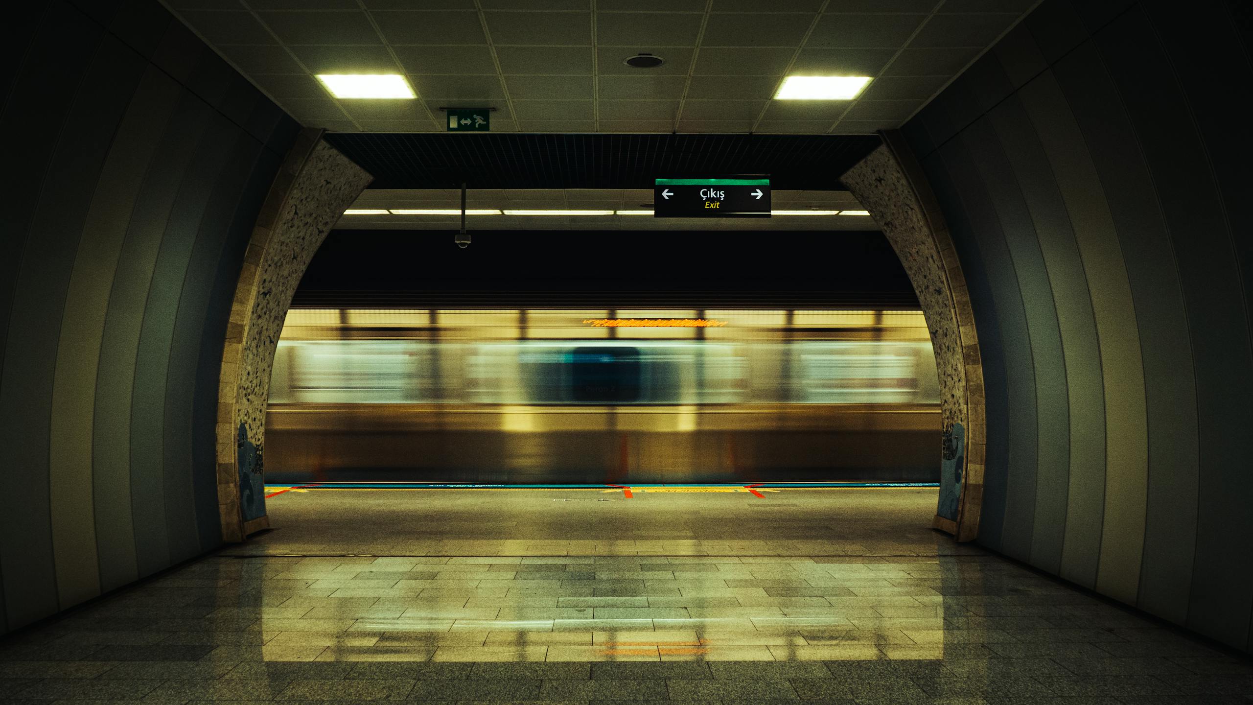 Blurred subway train passing through an empty Istanbul metro station, capturing urban motion.