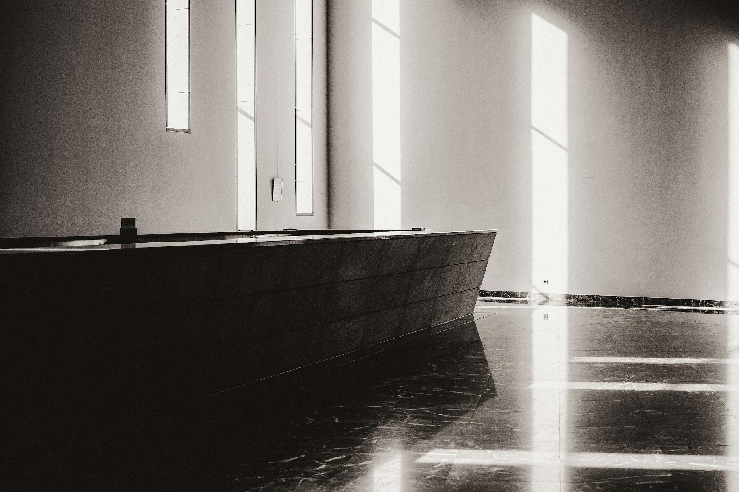 Interior of modern spacious bathroom with bath on tile floor next to windows