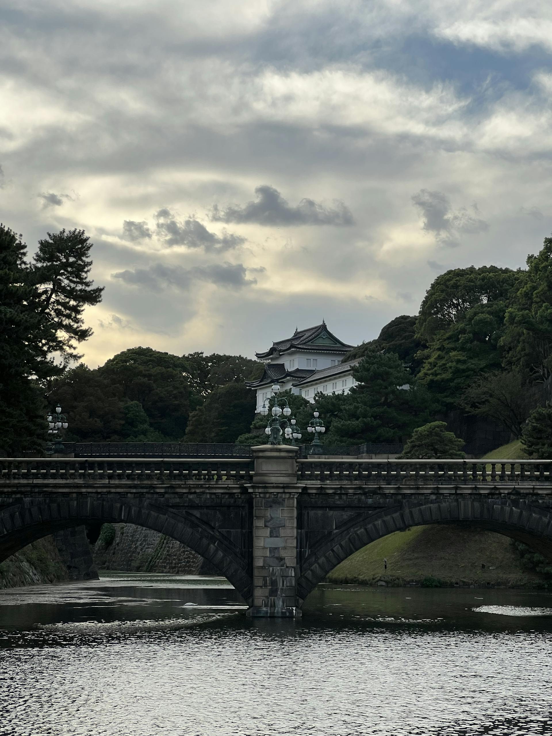Scenic view of Tokyo's Imperial Palace and Nijubashi Bridge under a dramatic sky.