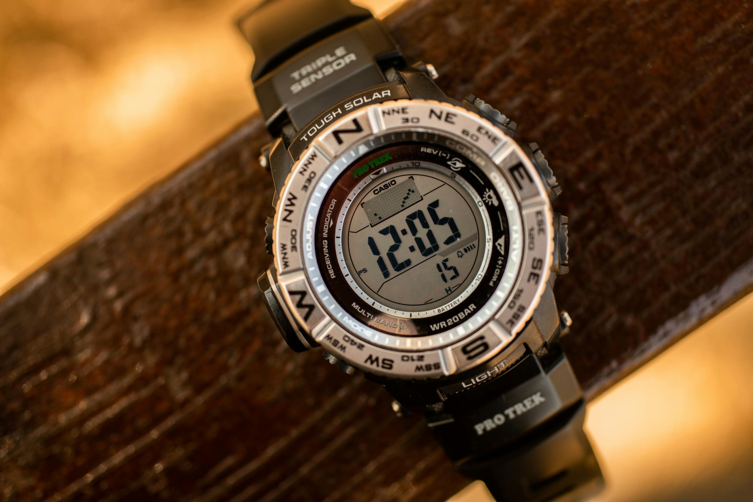 Close up of a digital wristwatch with compass markings on a wooden surface.