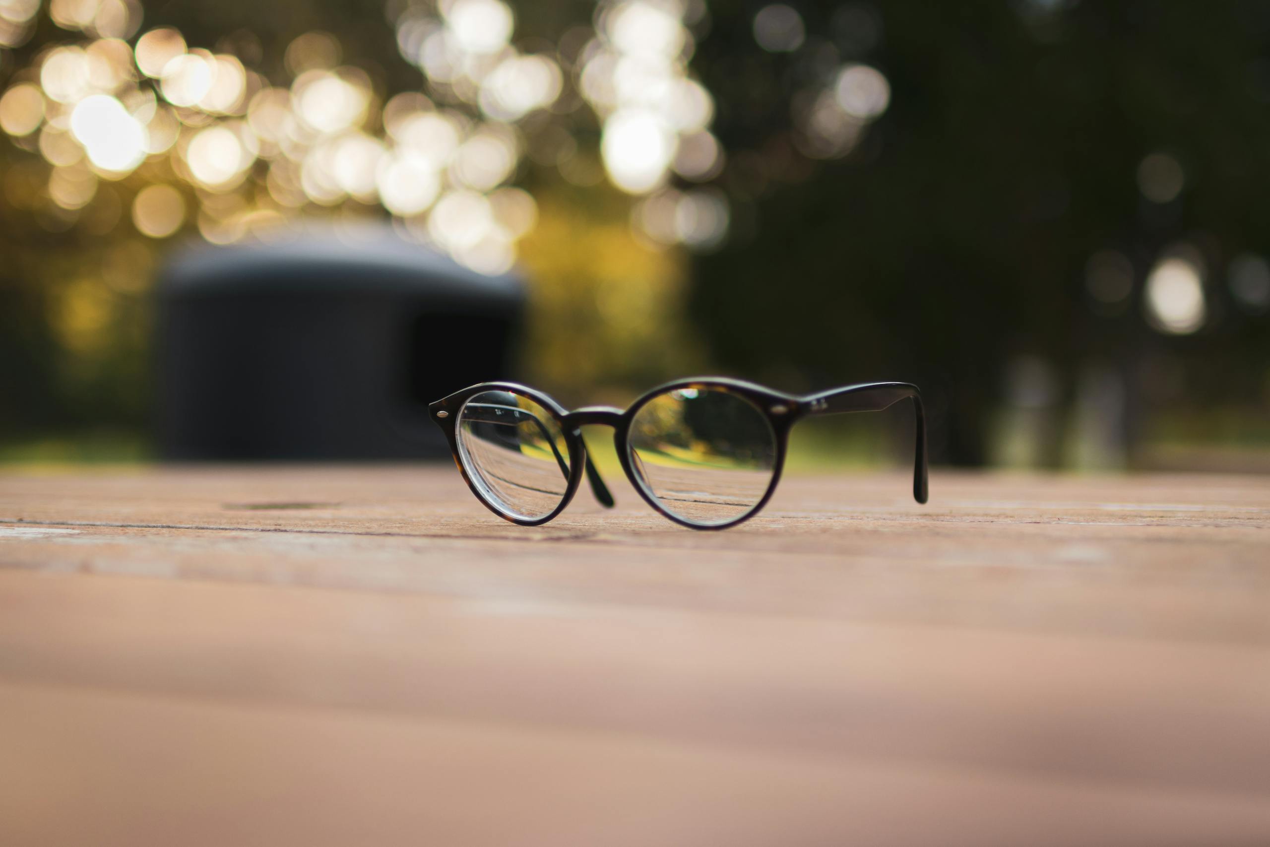 Close-up of stylish eyeglasses on a wooden surface with a blurred bokeh background.