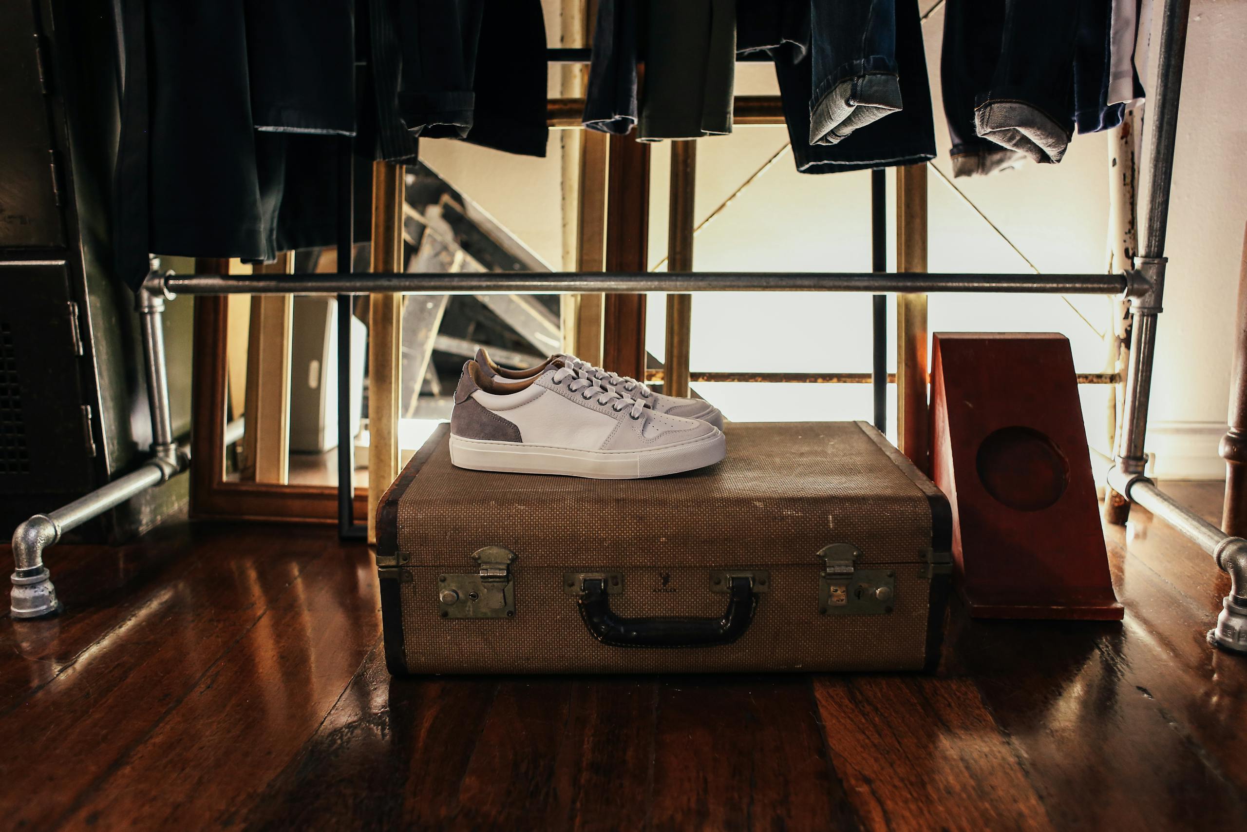 White sneakers resting on a vintage suitcase in a warmly lit room, invoking a retro vibe.