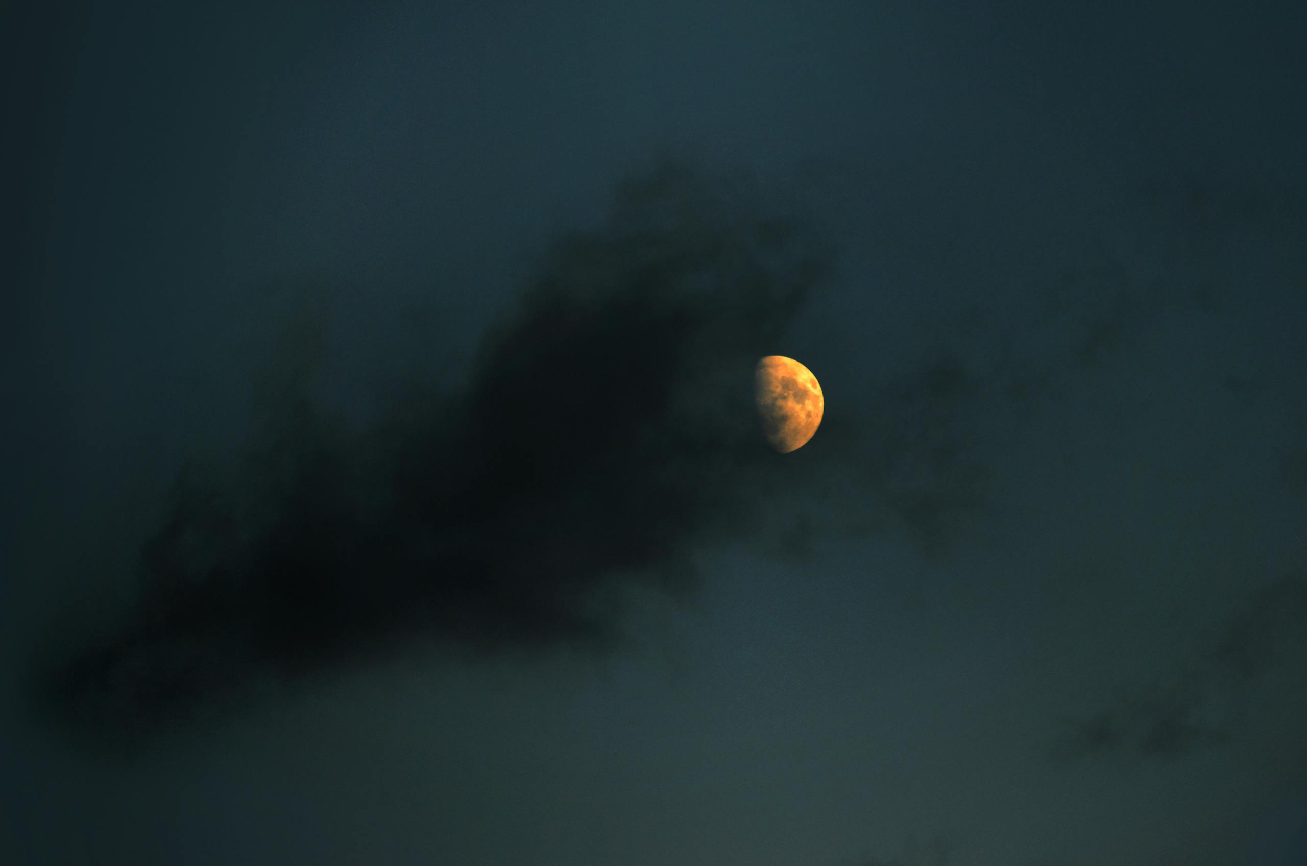 A mesmerizing view of the moon partially veiled by dark clouds in the serene night sky.