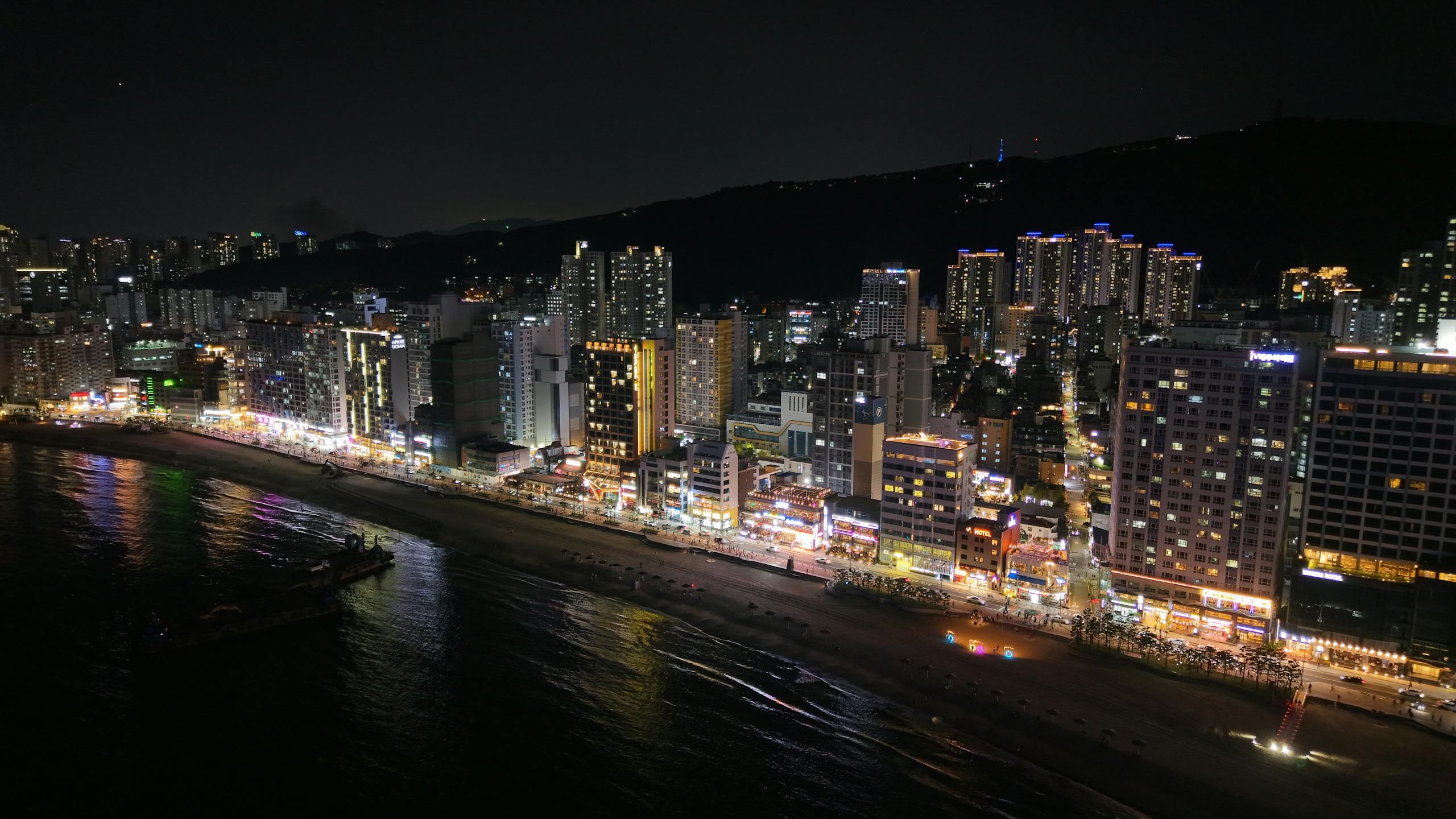 A stunning nighttime view of Busan's illuminated skyline and coastline in South Korea.