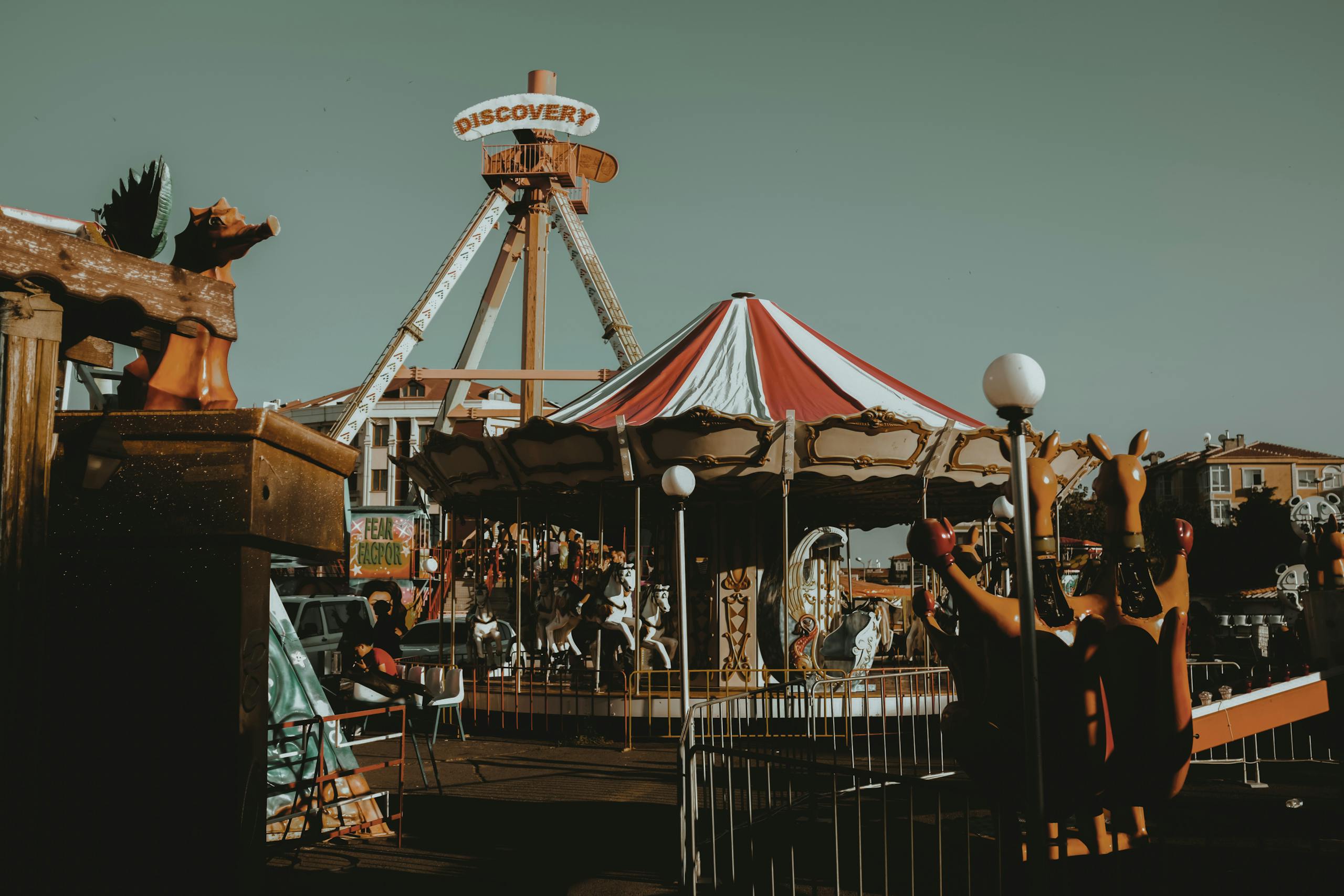 Colorful carousel and rides at an outdoor amusement park during the day.