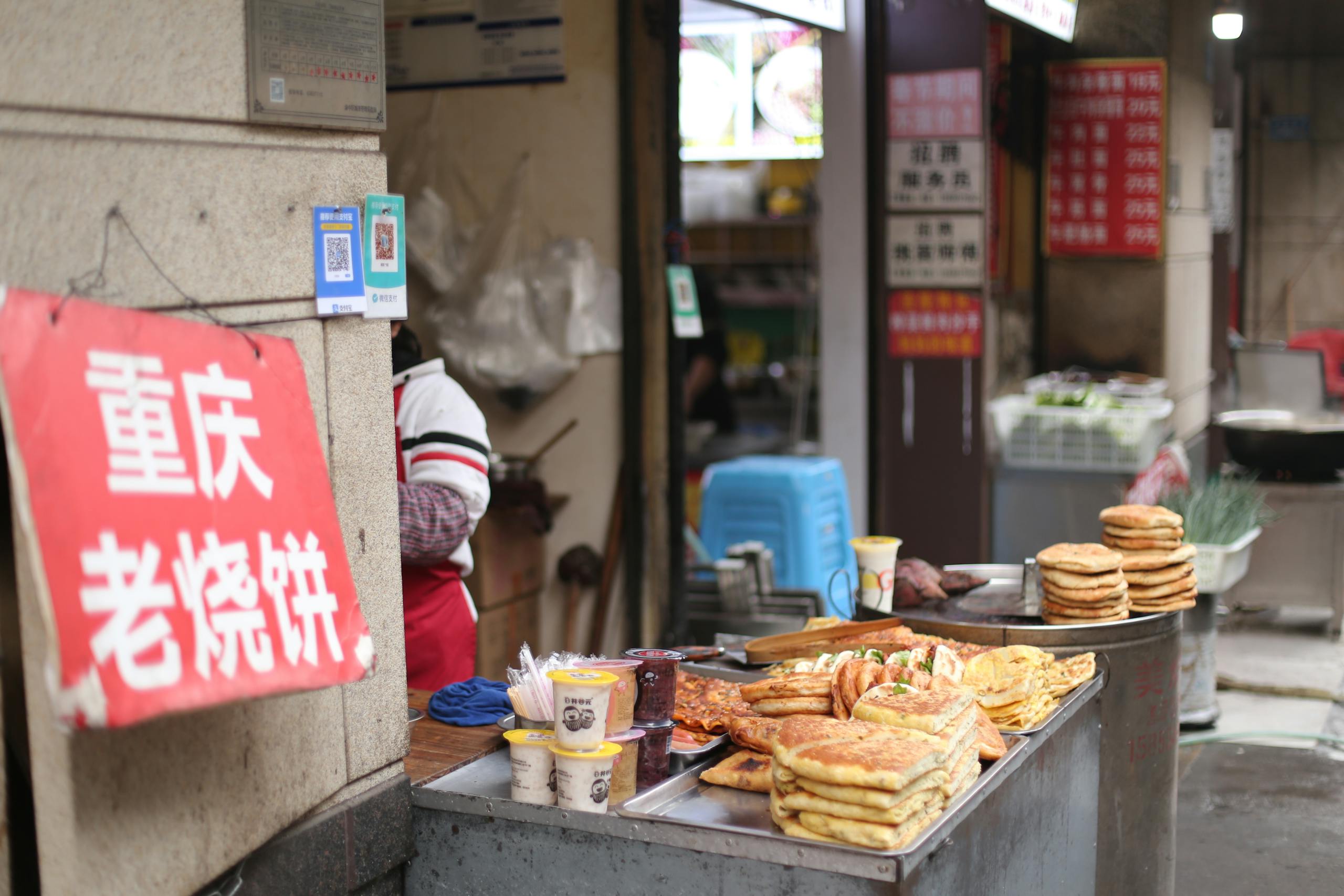A bustling street food stall offering traditional Chinese pancakes in an urban setting.