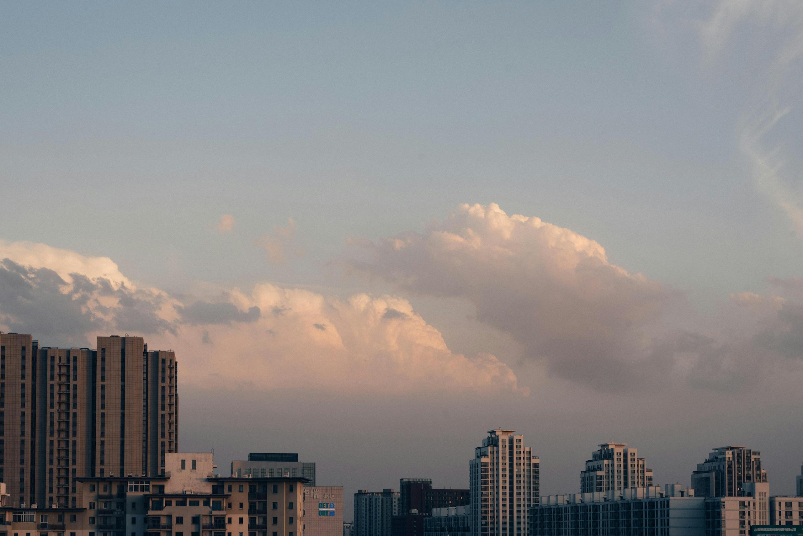A stunning view of Beijing's skyline at sunset featuring high-rise buildings and dramatic clouds.
