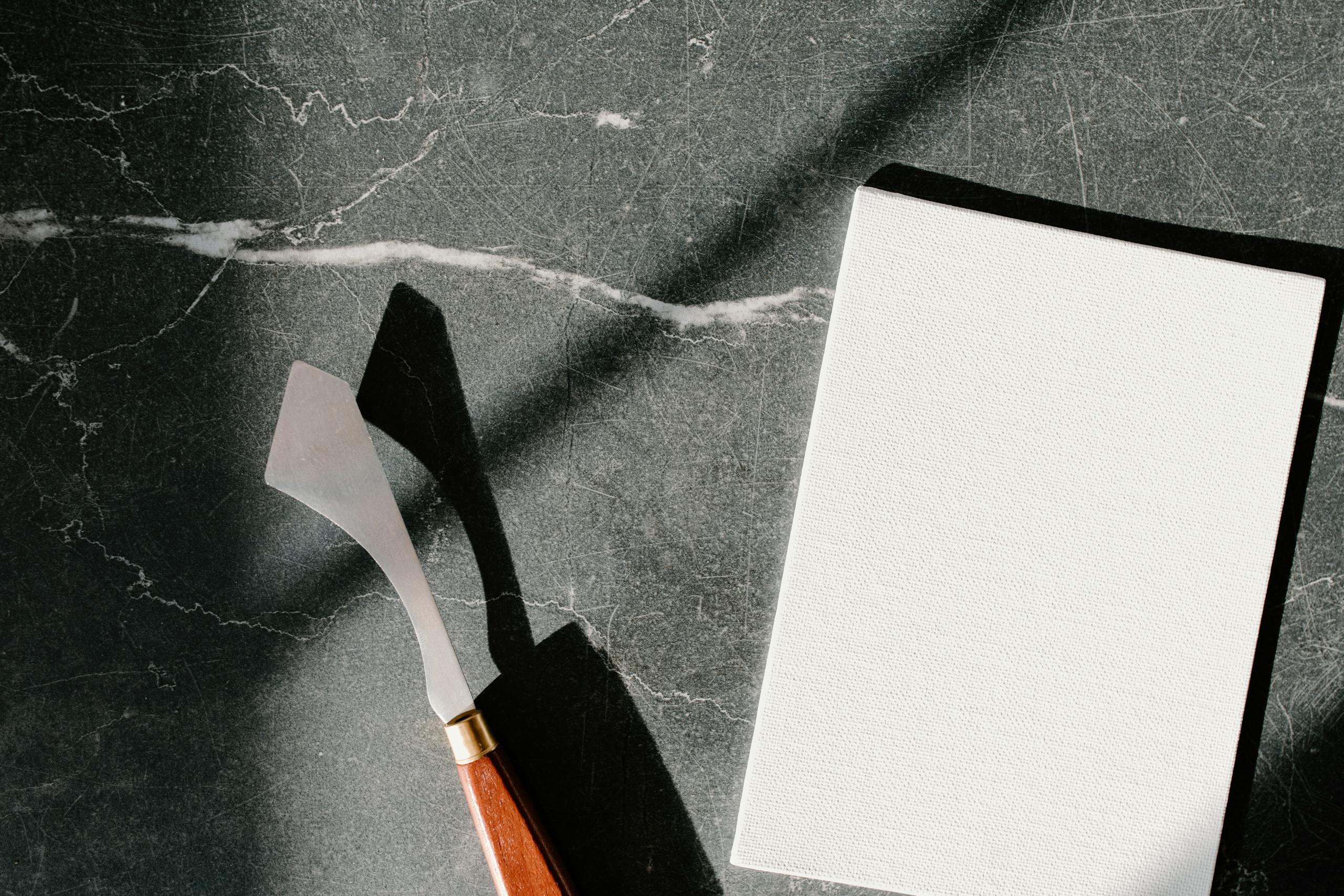 Palette knife and blank canvas on marble background, perfect for artistic projects.