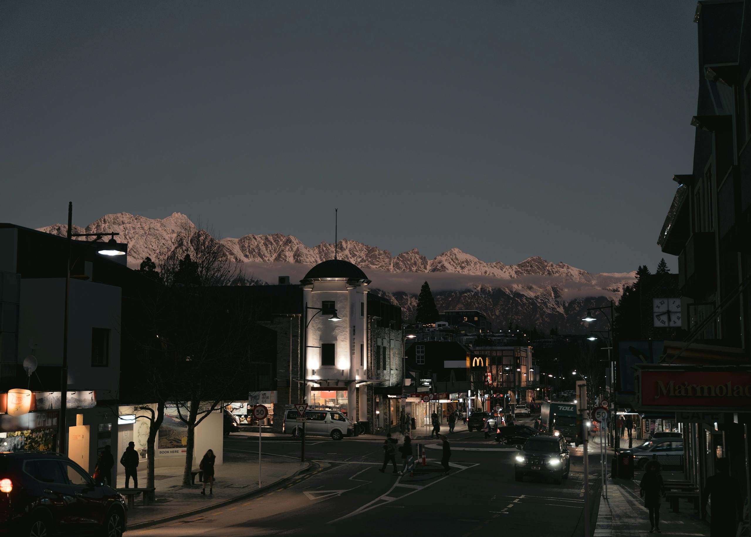 Discover Queenstown's charming streets against a majestic mountain backdrop at dusk.