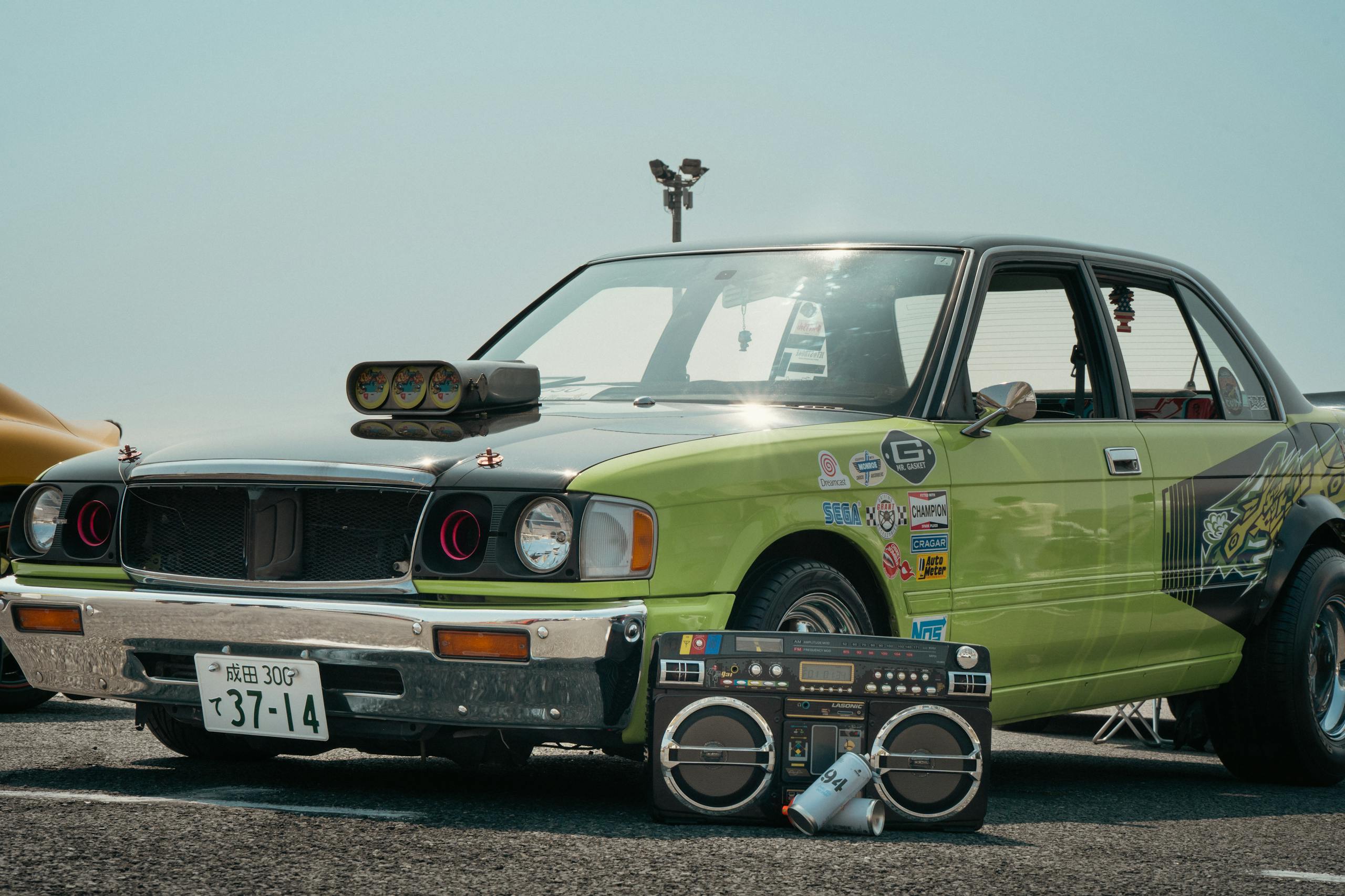 Vintage car with boombox at a Tokyo show. Retro vibes and unique customization.
