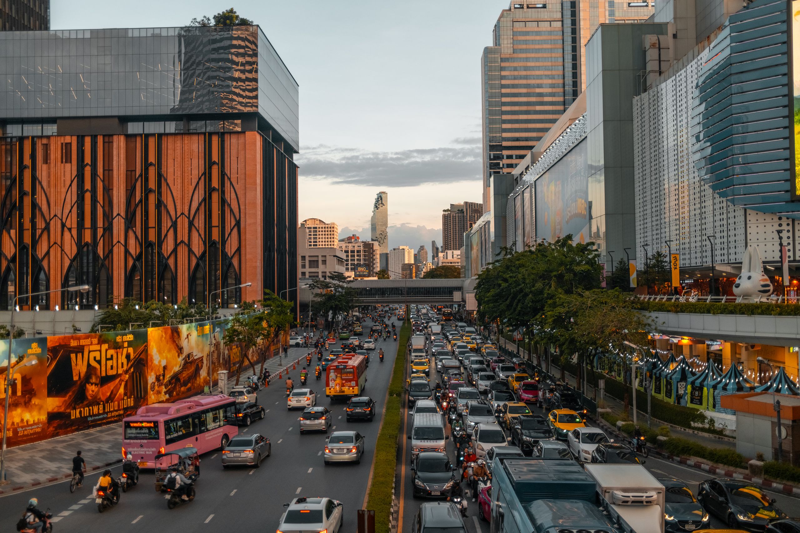 Vibrant cityscape of Bangkok at dusk with bustling traffic and skyline in view.