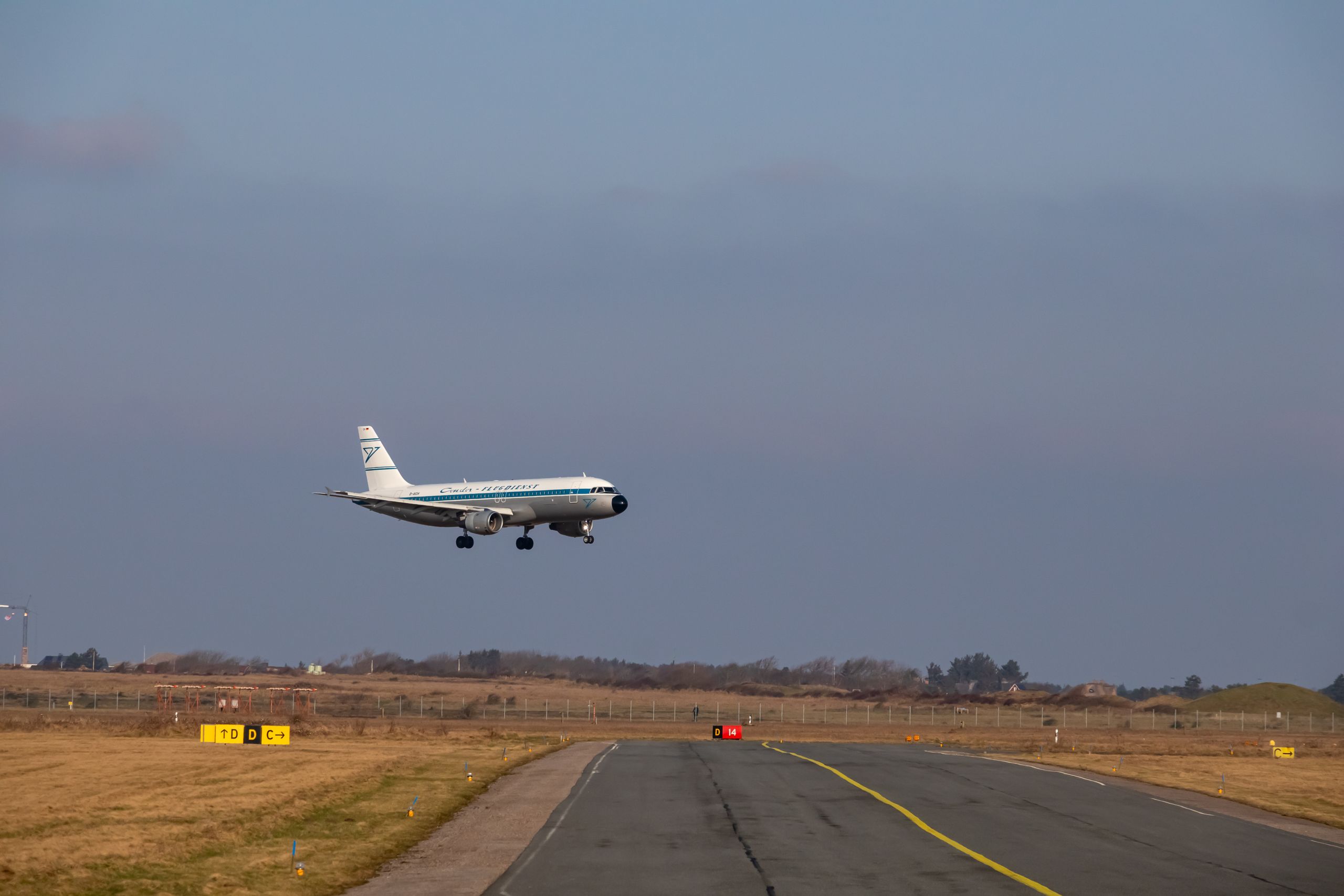 Airplane approaching runway for landing at airport with clear sky background.