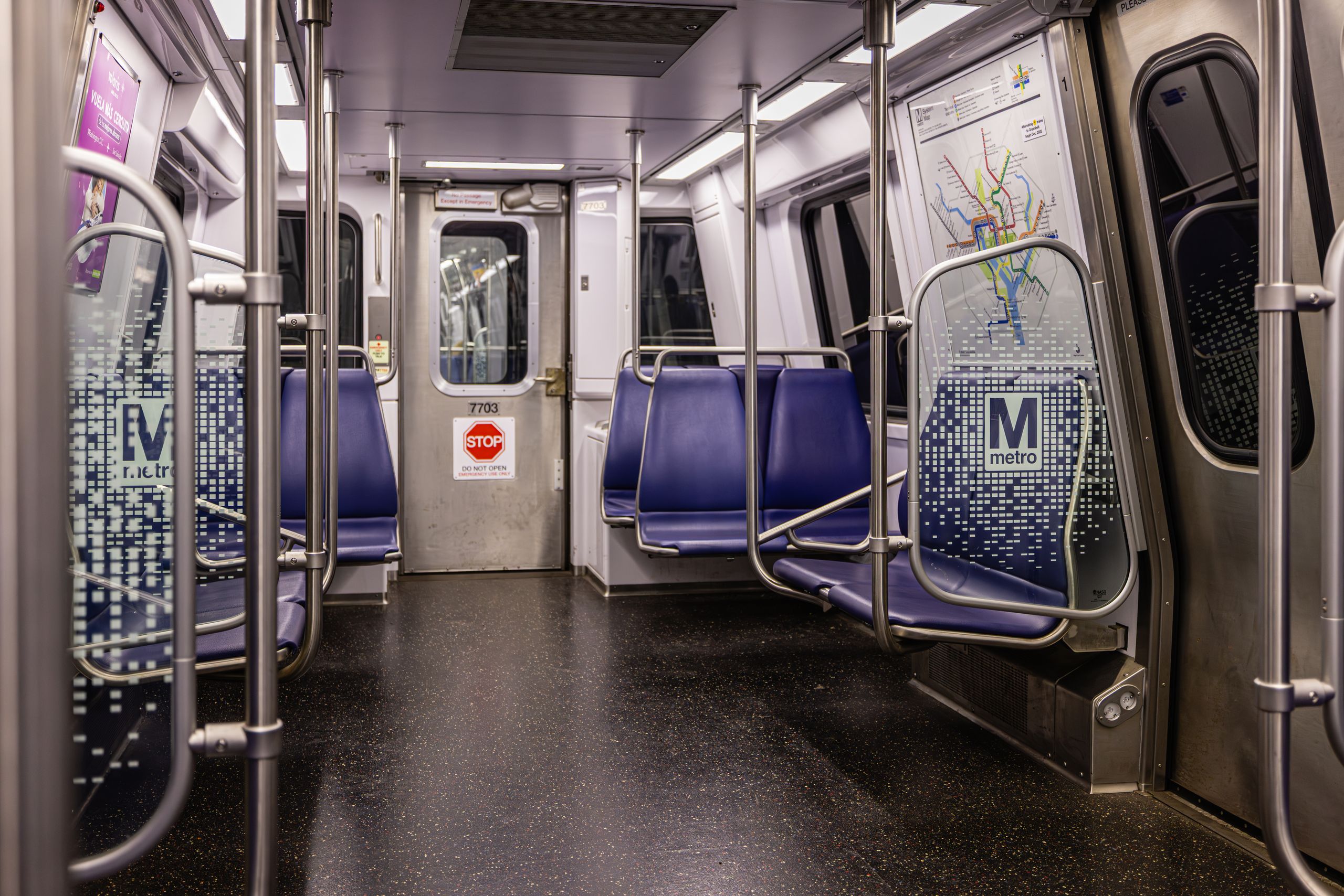 Interior view of an empty Washington DC Metro train car with blue seats and map display.