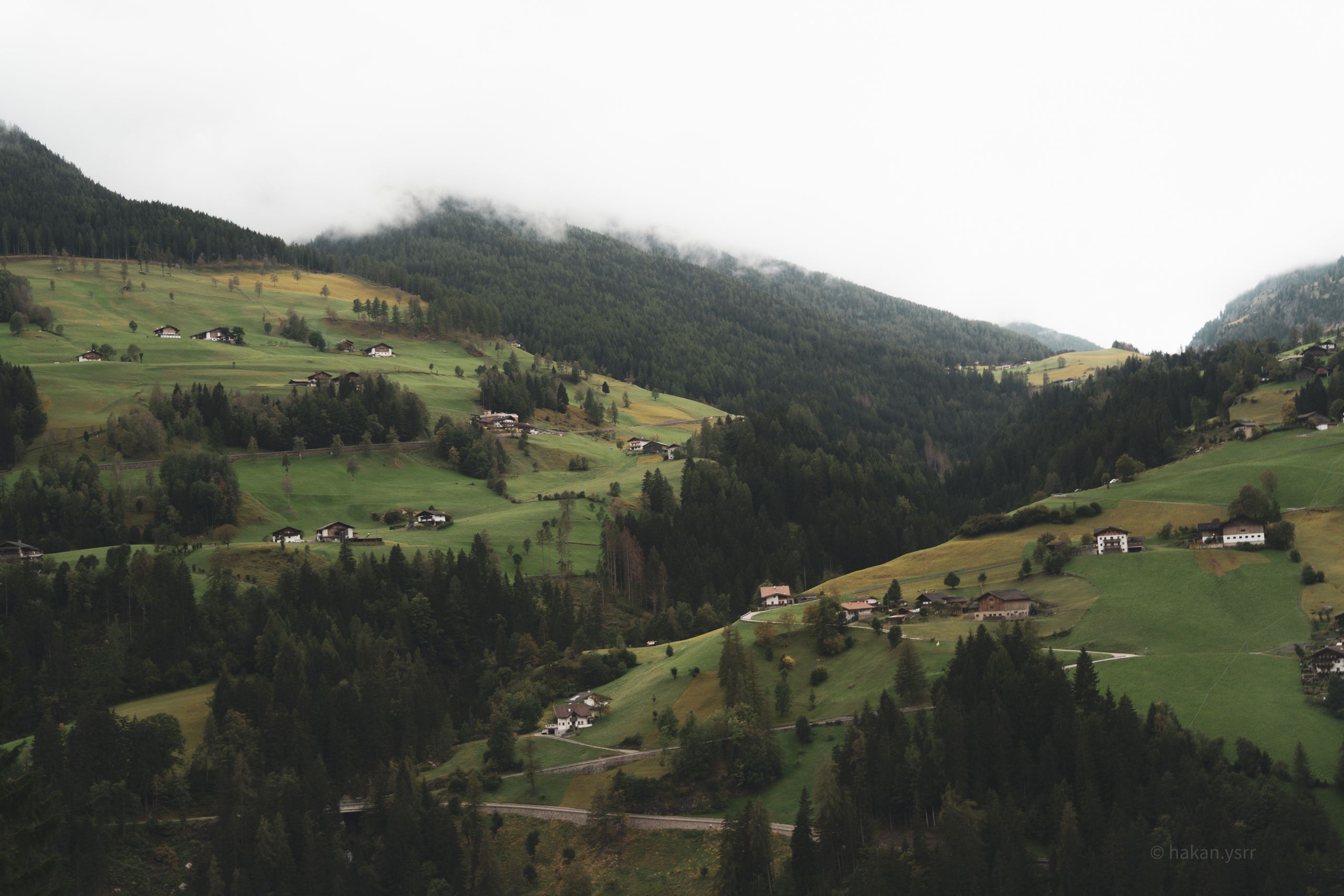 Explore a serene alpine landscape in Austria featuring rolling hills and traditional houses.