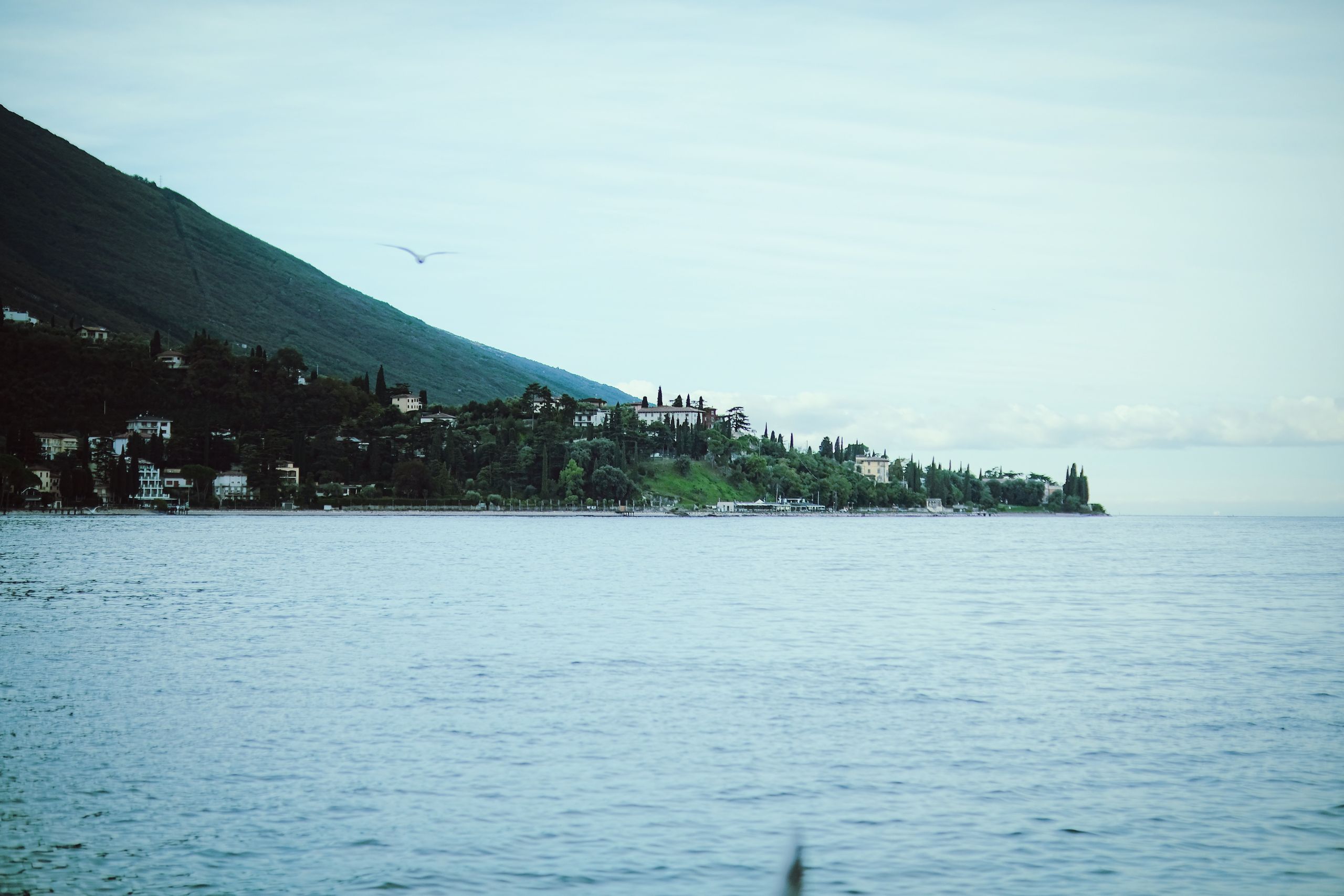 Picturesque landscape of Lake Garda with a distant island under a summer sky.