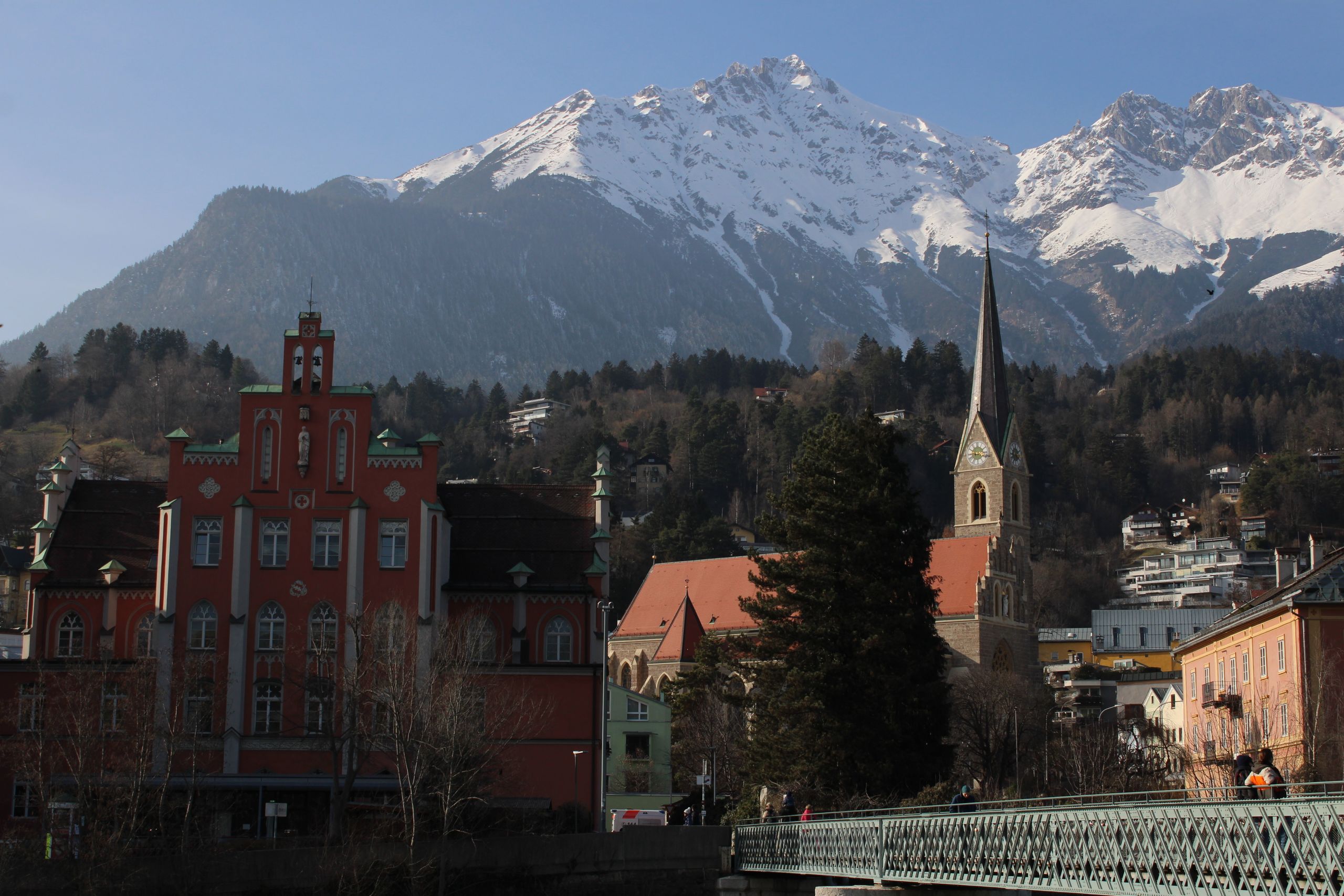 Picturesque town with mountain backdrop and church spire in winter setting.